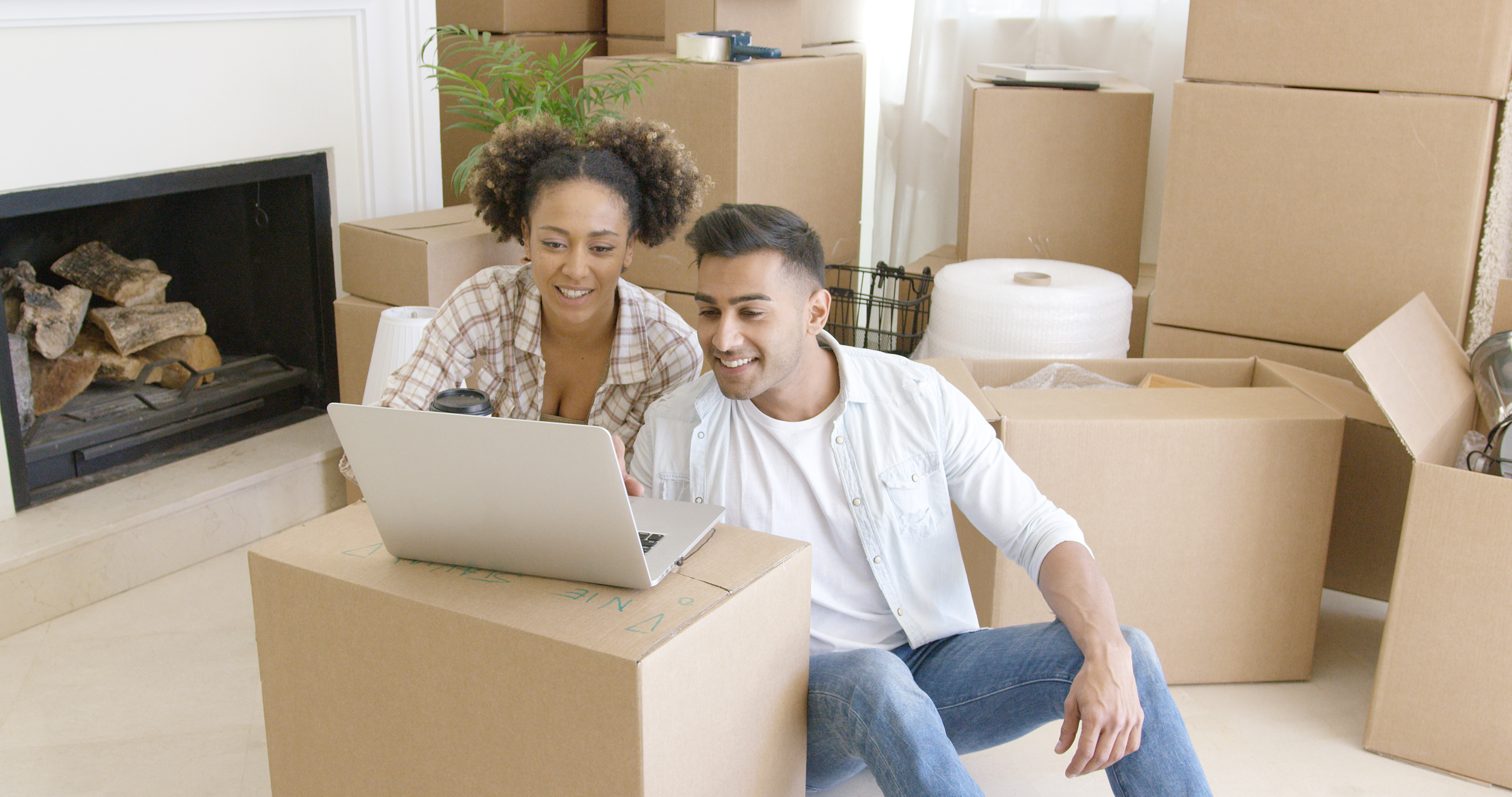 Couple with moving boxes engage with laptop